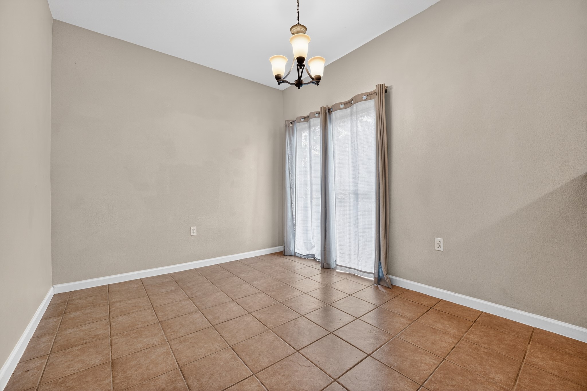 5625 Signal Point Austin, TX 78724 - Photo 13 of 33 A well-lit room features warm tile flooring and a classic chandelier, offering a versatile space for dining or gathering.