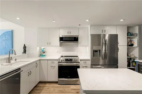 a kitchen with stainless steel appliances granite countertop a refrigerator a sink a stove a microwave and island