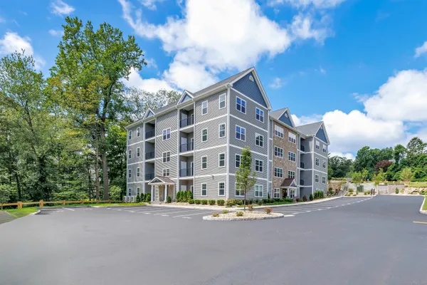 a front view of multi story residential apartment building with yard and traffic signal
