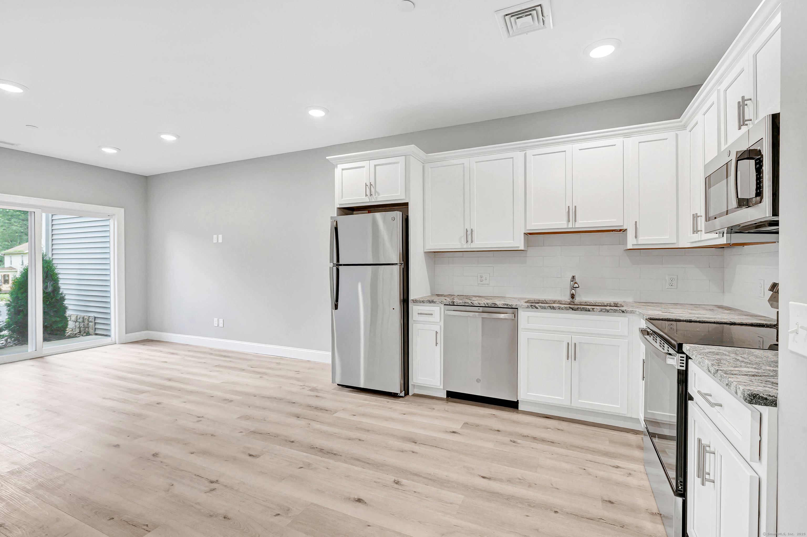 303 Bridgeport Avenue, Unit 205 Shelton, CT 06484 - Photo 28 of 36 a kitchen with granite countertop white cabinets and wooden floor