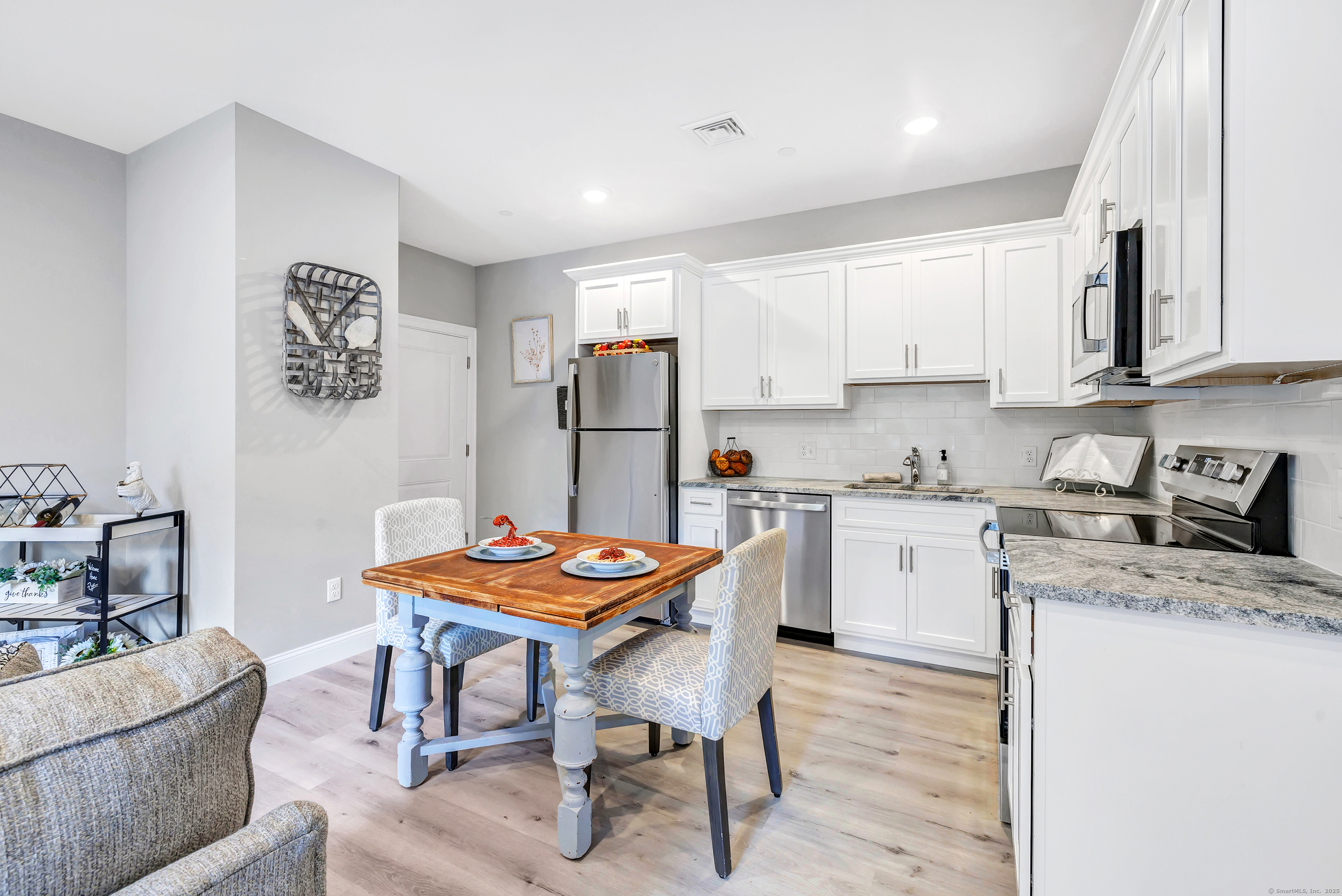 303 Bridgeport Avenue, Unit 205 Shelton, CT 06484 - Photo 7 of 36 a kitchen with a dining table chairs and white appliances