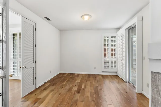 an empty room with wooden floor and windows