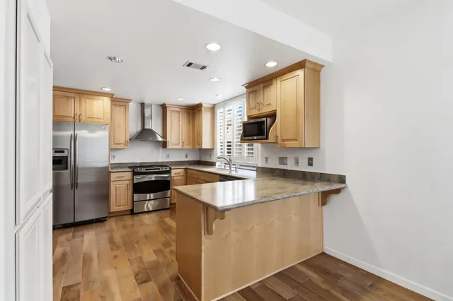 a kitchen with stainless steel appliances granite countertop a stove top oven a sink a refrigerator and white cabinets