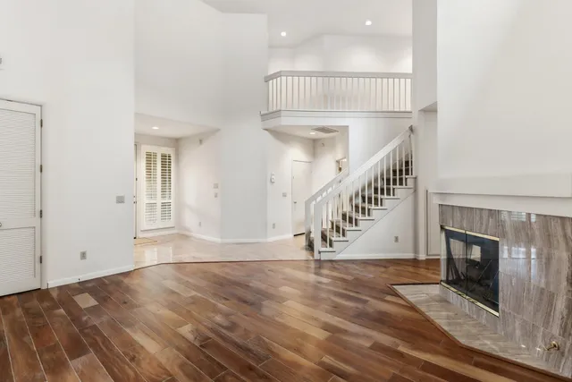a view of an empty room with wooden floor fireplace and a window