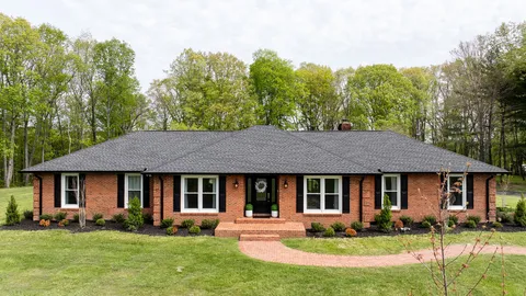 a view of brick house with a yard potted plants and a table