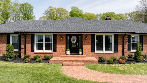 a front view of a house with a garden and trees