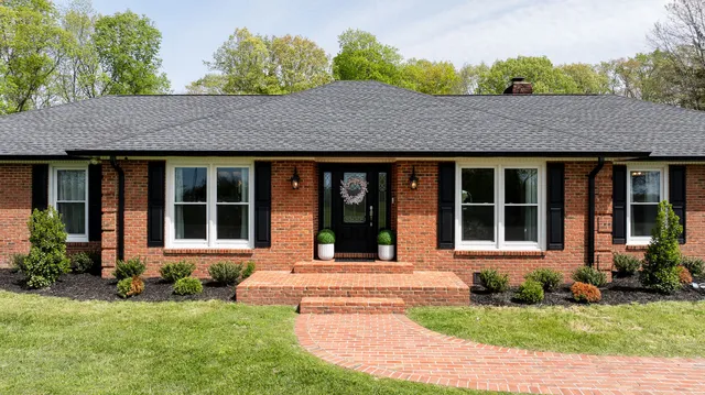 a front view of a house with a garden and trees
