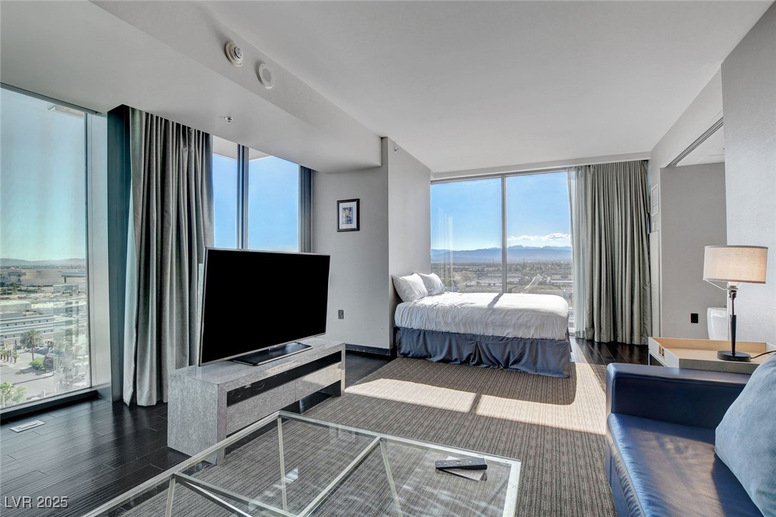 4381 West Flamingo Road, Unit 1121 Las Vegas, NV 89103 - Photo 10 of 33 Bedroom with floor to ceiling windows, wood finished floors, and multiple windows