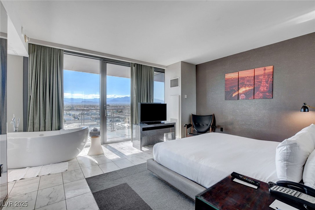 4381 West Flamingo Road, Unit 1121 Las Vegas, NV 89103 - Photo 14 of 33 Bedroom with access to outside, marble finish flooring, expansive windows, and a textured wall