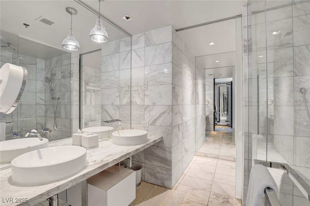 4381 West Flamingo Road, Unit 1121 Las Vegas, NV 89103 - Photo 17 of 33 Bathroom with tile walls, marble finish floors, double vanity, and a shower