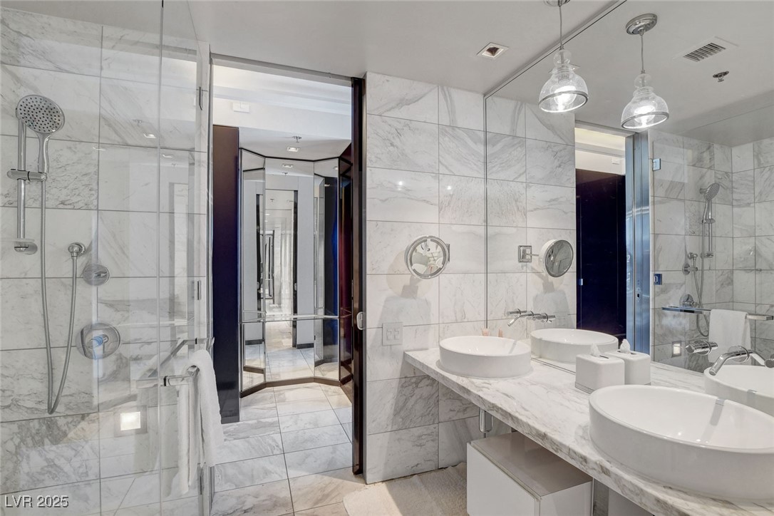4381 West Flamingo Road, Unit 1121 Las Vegas, NV 89103 - Photo 18 of 33 Bathroom with tile walls, a stall shower, marble finish flooring, and double vanity