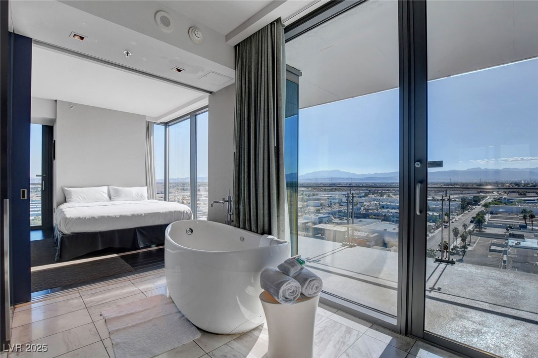 4381 West Flamingo Road, Unit 1121 Las Vegas, NV 89103 - Photo 1 of 33 Full bathroom featuring plenty of natural light, a freestanding bath, a mountain view, and expansive windows