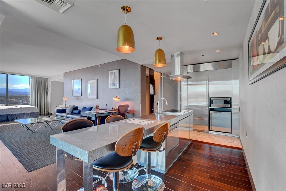 4381 West Flamingo Road, Unit 1121 Las Vegas, NV 89103 - Photo 2 of 33 Kitchen with a sink, island exhaust hood, light wood-type flooring, and built in appliances