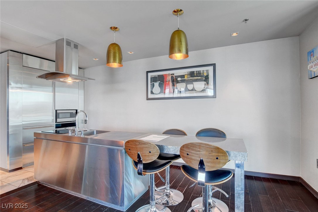 4381 West Flamingo Road, Unit 1121 Las Vegas, NV 89103 - Photo 4 of 33 Kitchen with baseboards, decorative light fixtures, wood finished floors, a sink, and island range hood