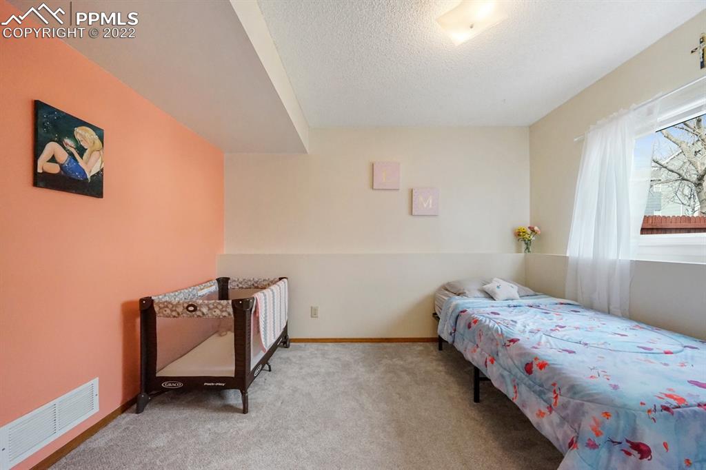 5805 Dutchess Drive Colorado Springs, CO 80923 - Photo 22 of 34 a bedroom with a bed and wooden floor
