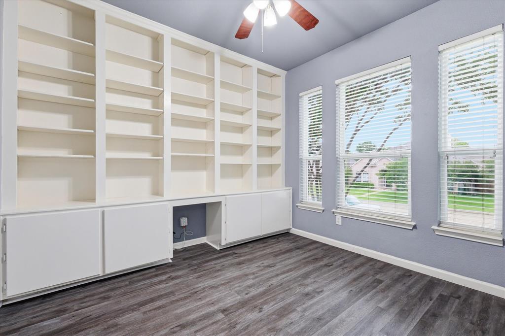 4545 Ridgepointe Drive The Colony, TX 75056 - Photo 31 of 37 Built-in shelving and cabinetry with a dedicated alcove, three windows with blinds, wood-finish flooring, and a ceiling fan with integrated lighting