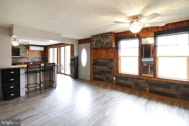 a large kitchen with stainless steel appliances granite countertop a refrigerator a sink dishwasher a dining table and chairs with wooden floor