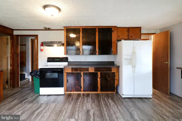 a kitchen with stainless steel appliances kitchen island granite countertop a stove top oven a sink dishwasher a dining table and chairs with wooden floor
