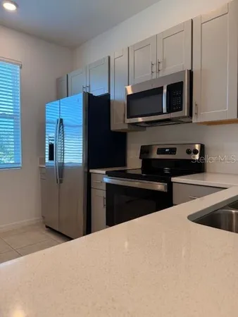 a kitchen with stainless steel appliances granite countertop a refrigerator a sink a stove a microwave and wooden cabinets