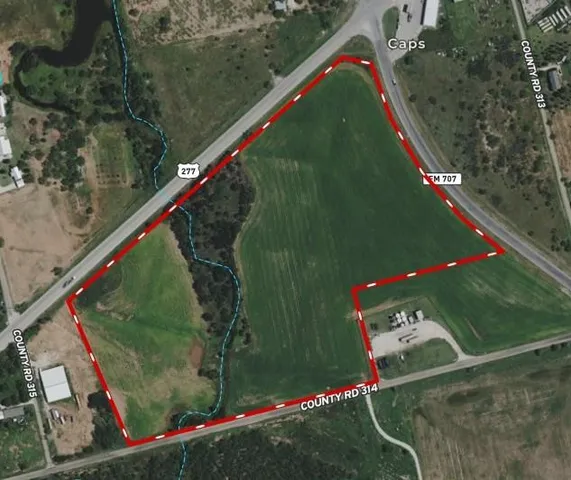 a green field with lots of trees in the background