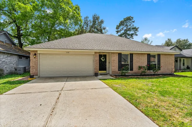 a front view of house with yard and trees in the background