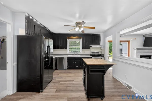 a kitchen with stainless steel appliances granite countertop a refrigerator a sink dishwasher a stove and a refrigerator with wooden floor