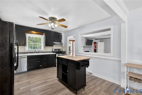a kitchen with a stove a sink a window and cabinets