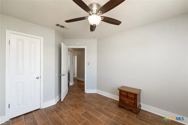 an empty room with wooden floor closet and ceiling fan