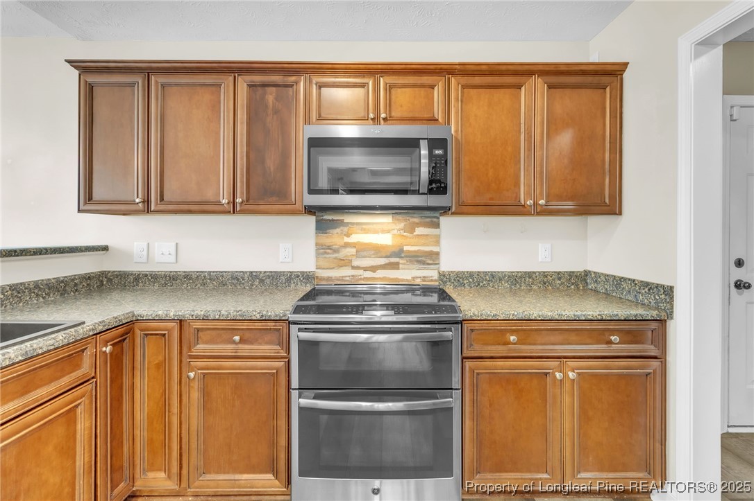 510 Hammond Farms Road Hope Mills, NC 28348 - Photo 12 of 49 a kitchen with granite countertop white cabinets and stainless steel appliances