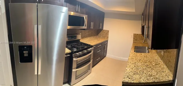 a kitchen with stainless steel appliances granite countertop a refrigerator and a stove