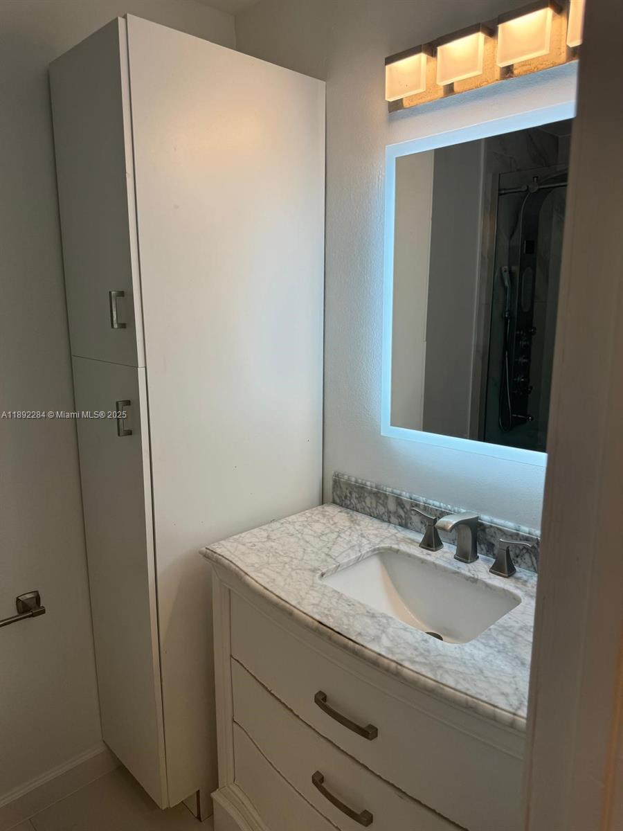 18101 Northwest 68th Avenue, Unit D207 Hialeah, FL 33015 - Photo 14 of 18 a bathroom with a granite countertop sink and a mirror