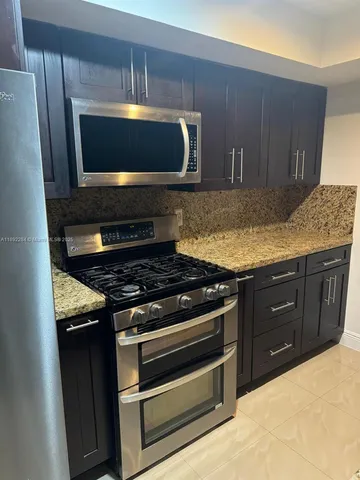 a kitchen with granite countertop a stove and a microwave
