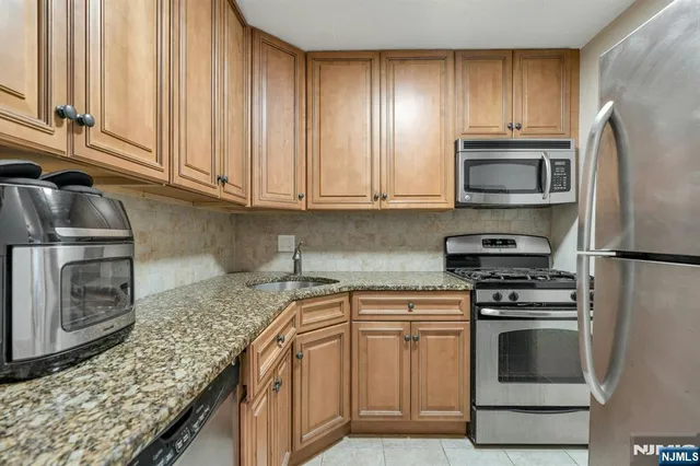 a kitchen with granite countertop a stove sink and refrigerator