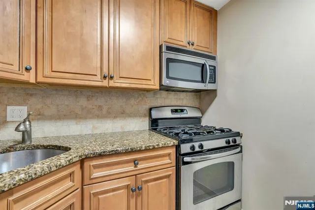 a kitchen with granite countertop cabinets stainless steel appliances and a sink