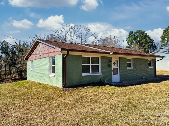 a front view of house with yard and trees in the background