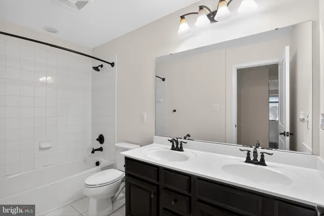 a bathroom with a double vanity sink toilet mirror and bathtub