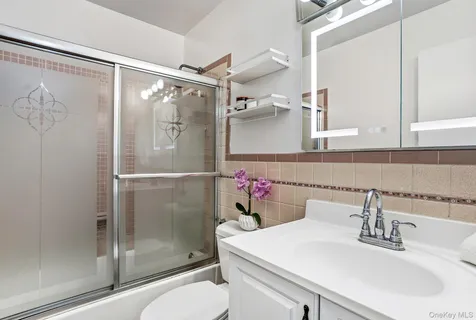 a bathroom with a shower sink mirror and toilet