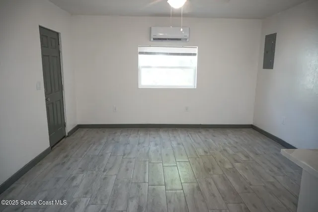 an empty room with wooden floor and windows