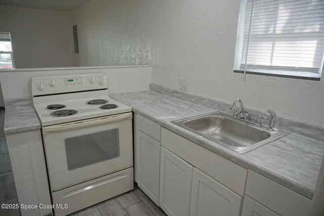 a kitchen with granite countertop white cabinets stove and sink