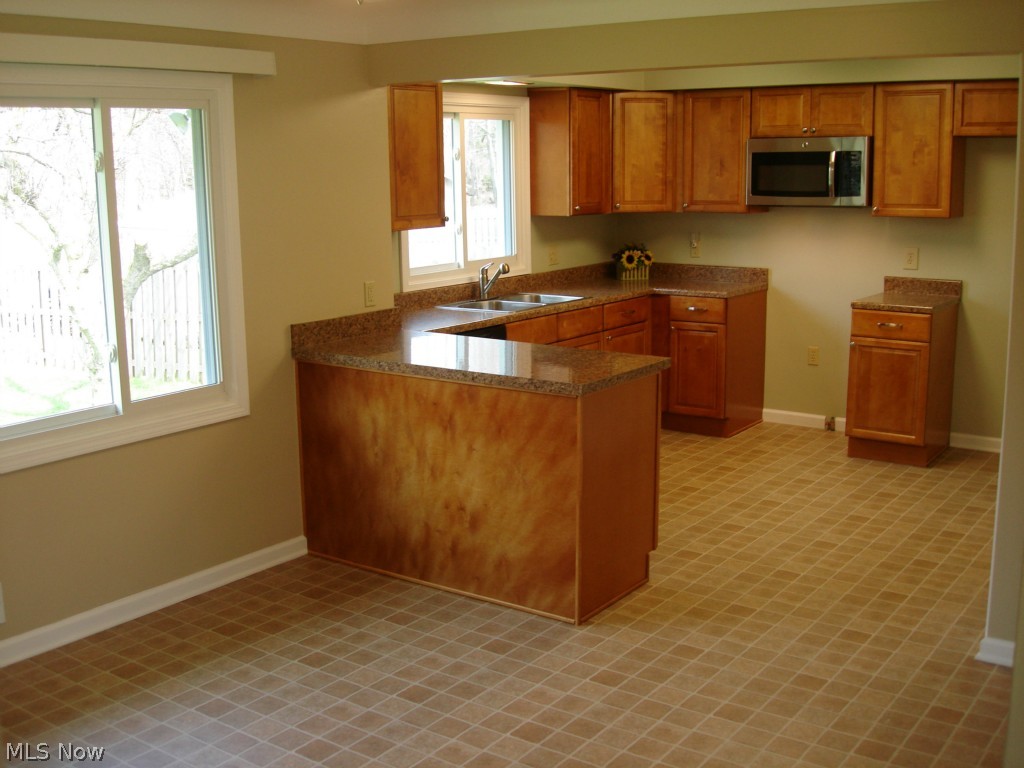 10418 Biddulph Road Cleveland, OH 44144 - Photo 9 of 25 KITCHEN COMPLETELY REMODELED WITH MAPLE CABINETS, SLOW DRAWER CLOSERS, DOUBLE BOWL STAINLESS STEEL SINK WITH PULL OUT FAUCET, GE DISHWASHER, GE MICROWAVE, 25 YEAR ARMSTRONG VINYL FLOORS, ALL UPDATED PLUMBING AND ELECTRICAL.