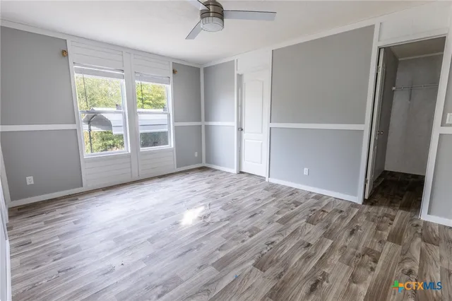 an empty room with wooden floor cabinet and windows