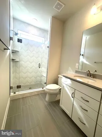 a bathroom with a granite countertop sink a toilet and a mirror
