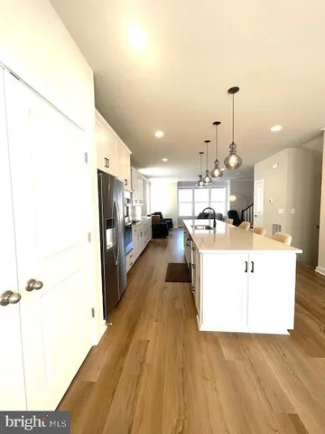 a view of kitchen with stainless steel appliances kitchen island a sink wooden floor and living room view