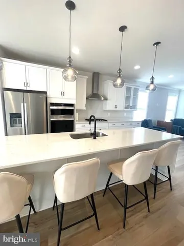 a kitchen with stainless steel appliances kitchen island granite countertop a table chairs and a sink