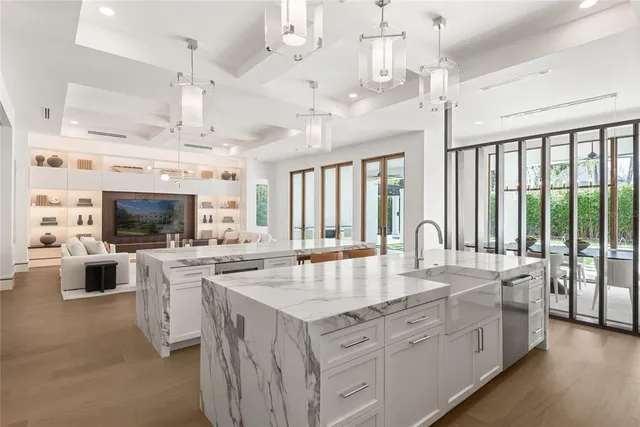 a large white kitchen with a large island in the center and stainless steel appliances