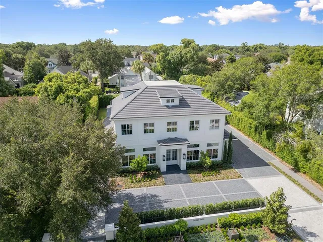 a view of a house with a small yard plants and large trees