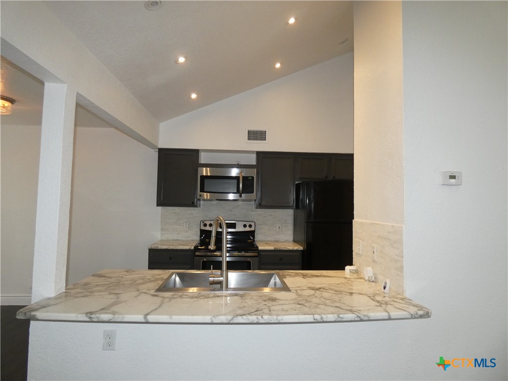 14745 Babcock Road San Antonio, TX 78249 - Photo 6 of 25 a kitchen with kitchen island granite countertop a sink and a refrigerator