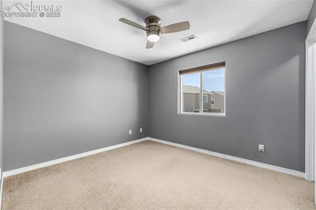 an empty room with ceiling fan and windows