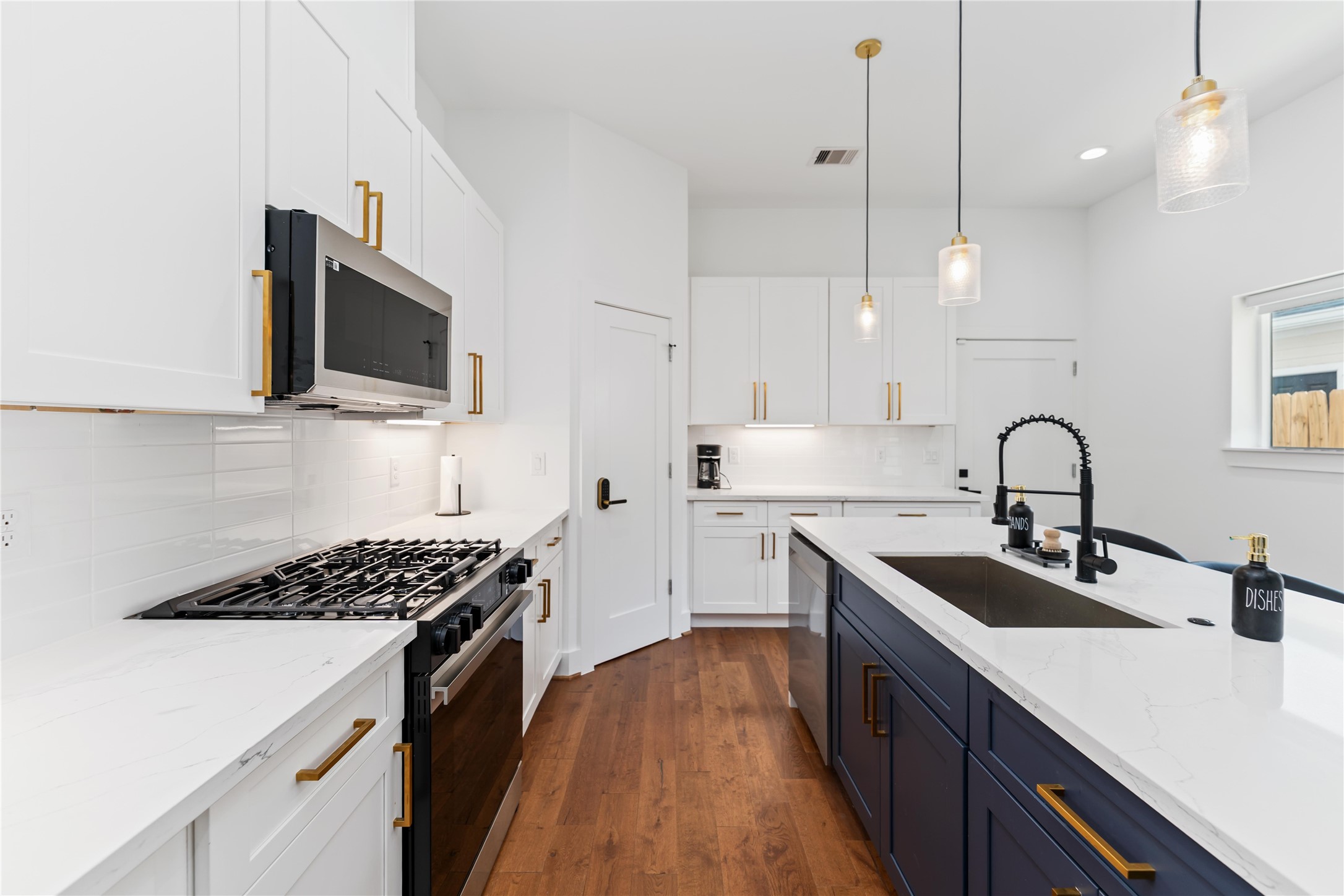 3040 Webster Street Houston, TX 77004 - Photo 3 of 18 a kitchen with kitchen island stainless steel appliances a sink a stove and a wooden floors