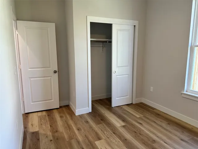 a view of a room with wooden floor and closet area